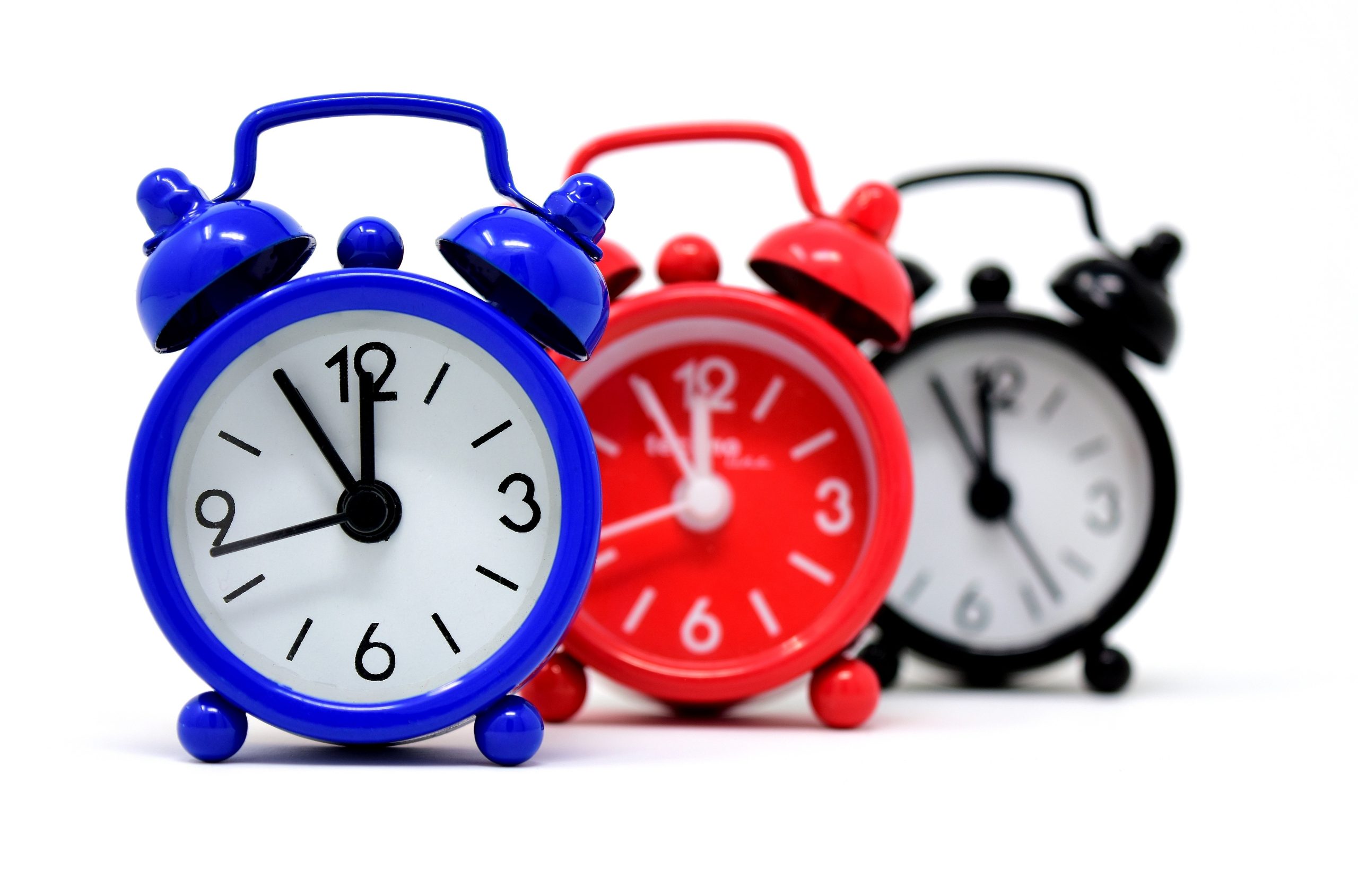 photo showing three different colored clocks - red, blue and black