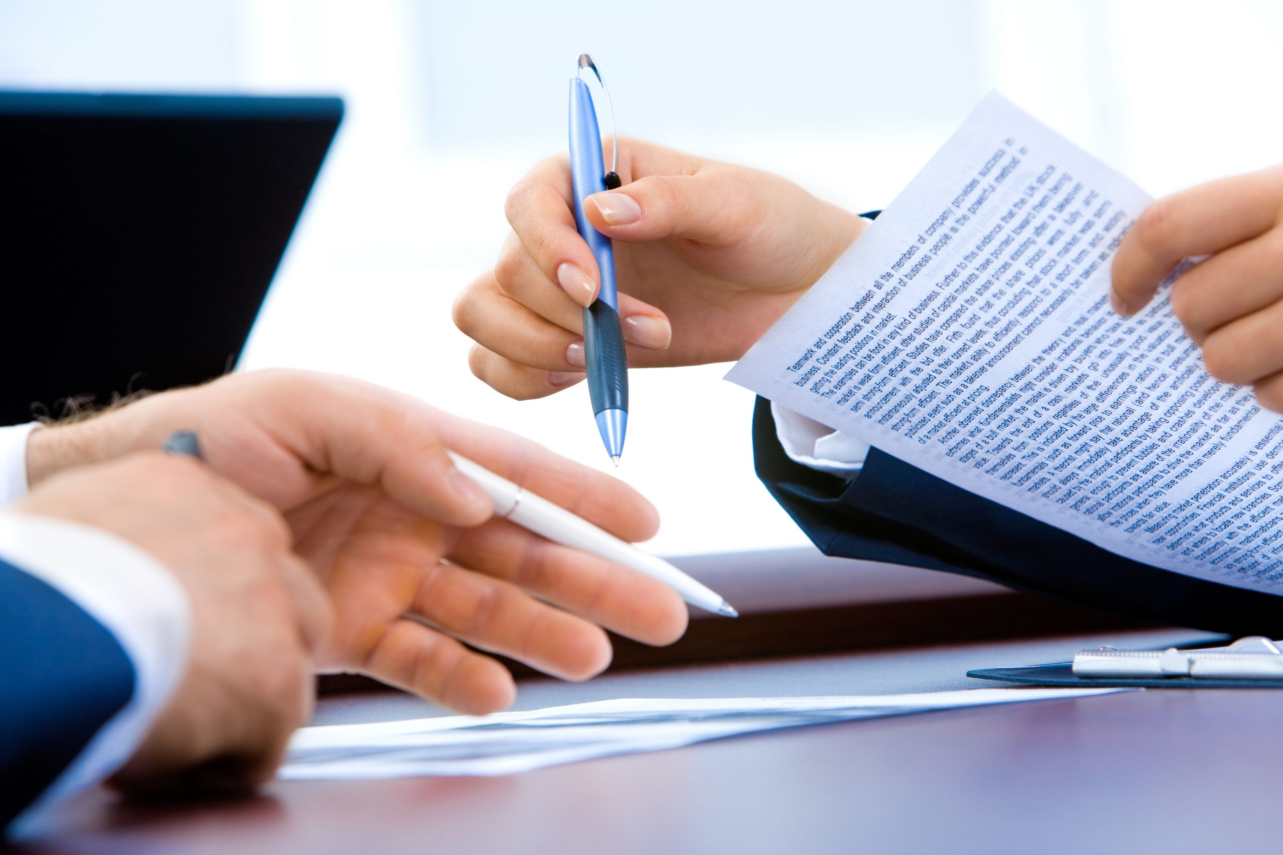 Shows two people signing documents and handing over a pen